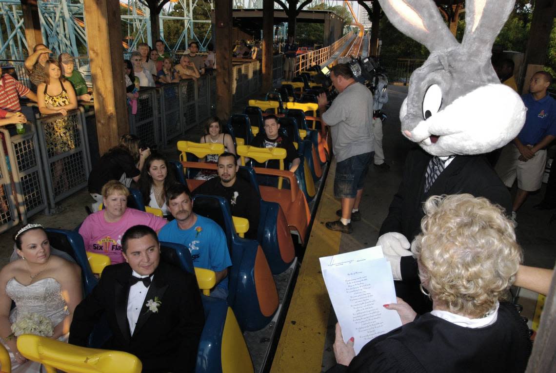 July 7, 2007: Couples (from front) Shelley Castillo and John Williams, Lori Cooper and Allen Hanks, Sonia Montano and Paul Benavides, Allison Honea and Sean Webb recite their vows on the Titan ride with Judge Linda Davis. Six Flags Over Texas played wedding host to seven couples in the Thrilled Ever After: A Wedding to Remember!