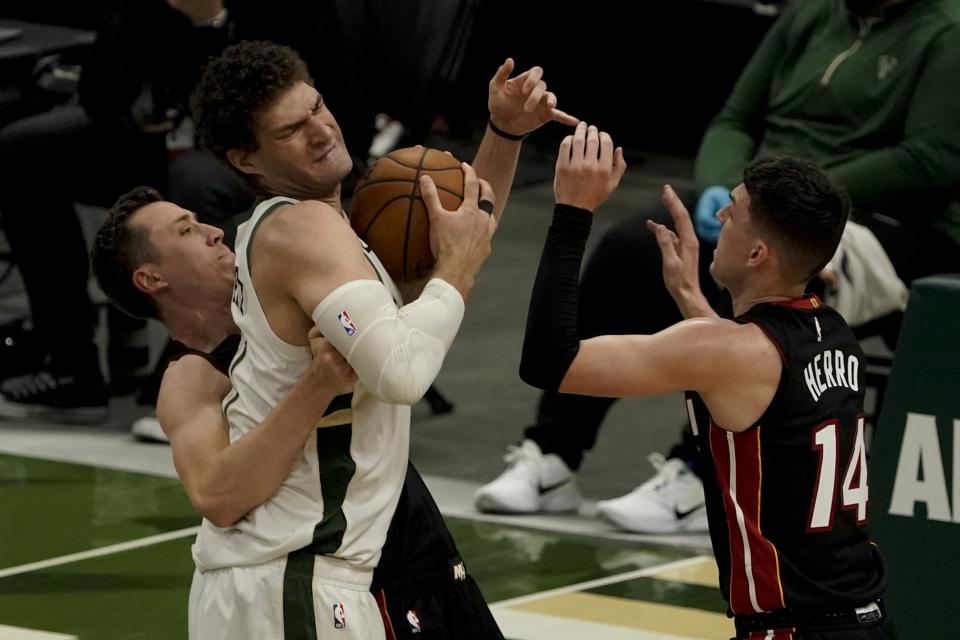 Miami Heat's Duncan Robinson fouls Milwaukee Bucks' Brook Lopez during the first half of an NBA basketball game Saturday, May 15, 2021, in Milwaukee. (AP Photo/Morry Gash)