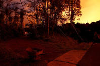 Downed power lines and a wheelbarrow are seen by a dirt road, illuminated by lava from the Kilauea volcano, in the Leilani Estates near Pahoa, Hawaii, U.S., May 26, 2018. REUTERS/Marco Garcia