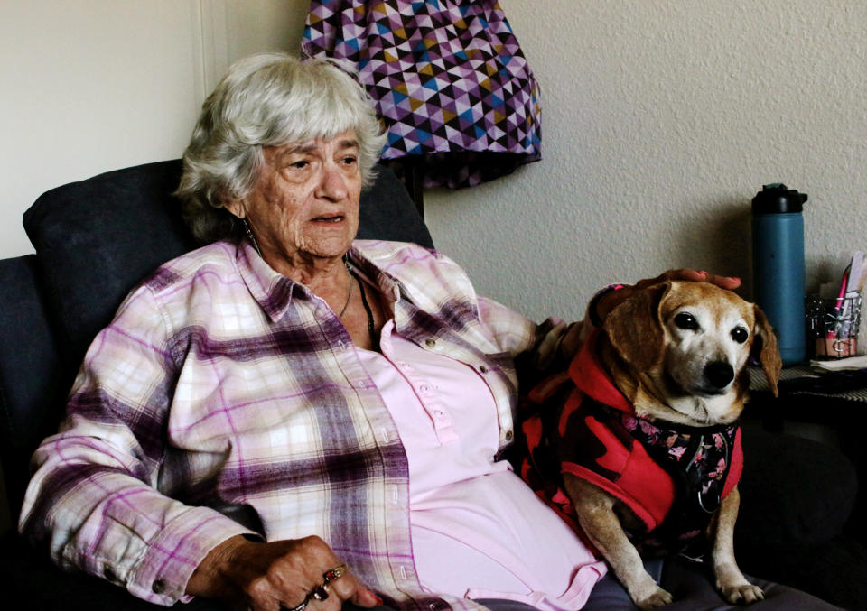 Kasey Dungan, 73, holds her 11-year-old mixed dachshund Sandy in a subsidized Phoenix apartment for older adults on Monday, Dec. 12, 2022. She says she feels fortunate to be with her dog in her home after falling into homelessness early this year. But high costs for food and other bills mean her entire Social Security check is gone by month's end. (AP Photo/Cheyanne Mumphrey)