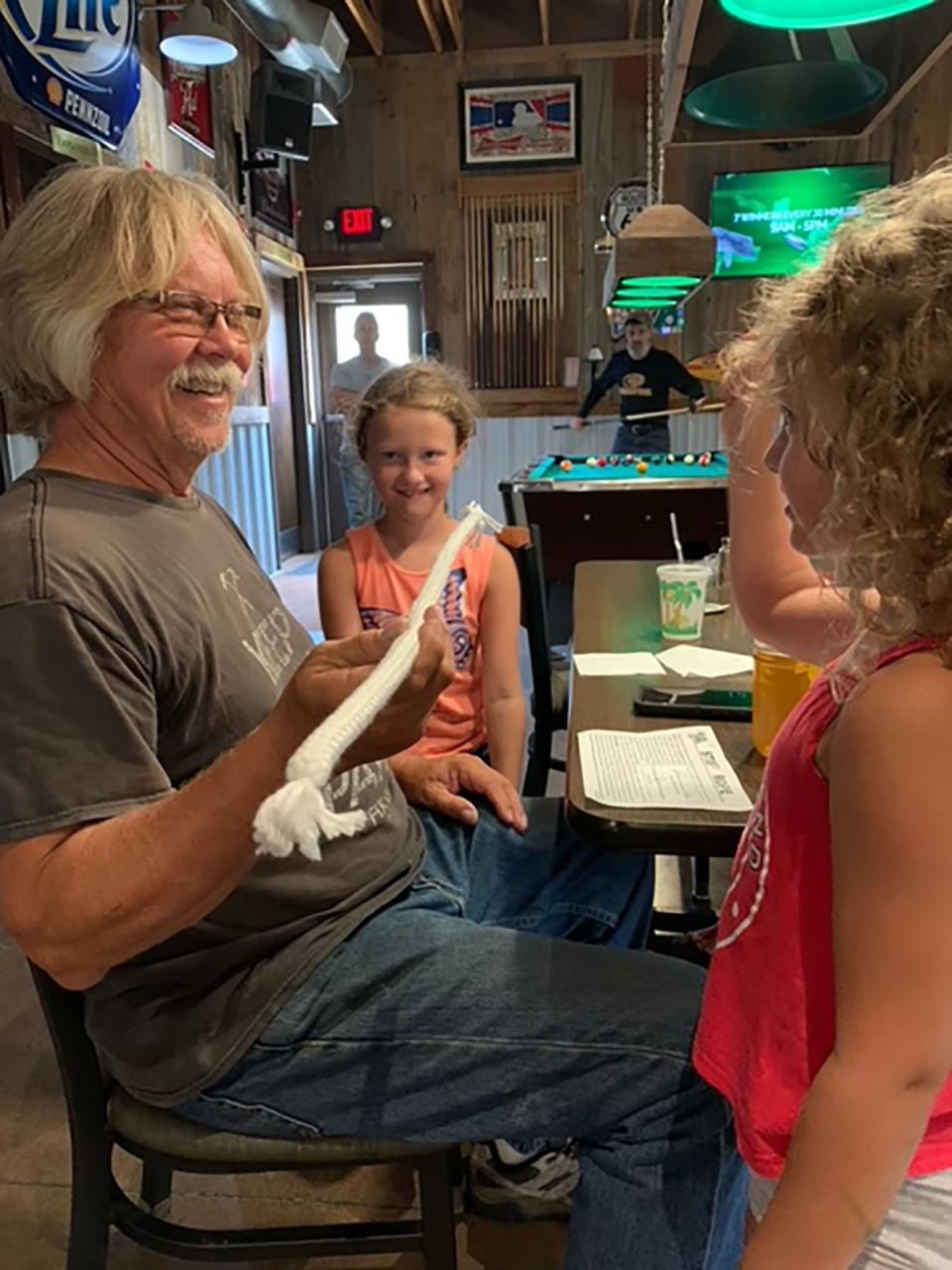 Colon seasonal resident Mike Gierman impresses his granddaughters, Reese, 7, and Vivienne, 5, with a rope trick he purchased Wednesday at Abbot's Magic in Colon. They enjoyed lunch at Curly's after taking in activities related to Abbott's Magic Get-Together.