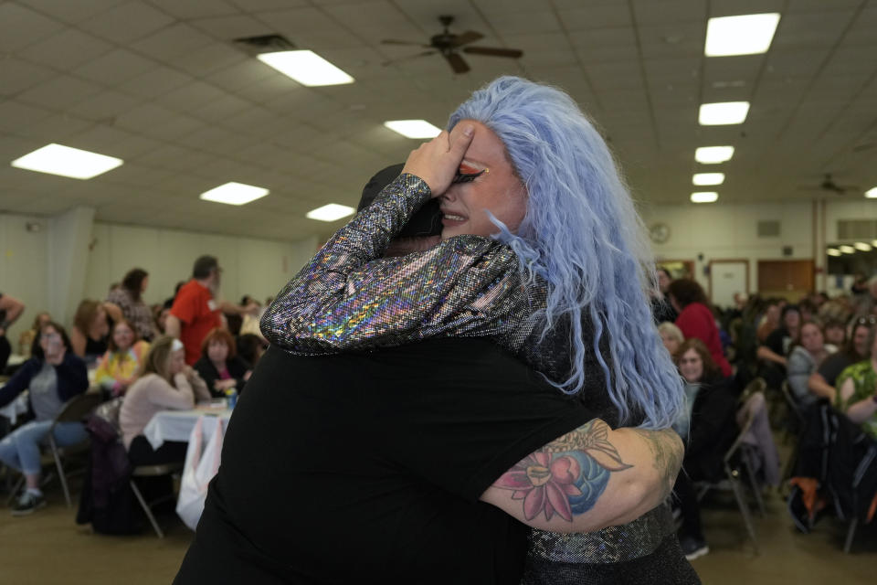 Drag queen Trixy Valentine, aka Jacob Kelley, cries in the arms of DJ Corrine after performing their drag story mix at a "Drag Bingo" fundraiser at the Nescopeck Township Volunteer Fire Company Social Hall, in Nescopeck, Pa., Saturday, March 18, 2023. Trixy's emotional performance received a standing ovation. (AP Photo/Carolyn Kaster)