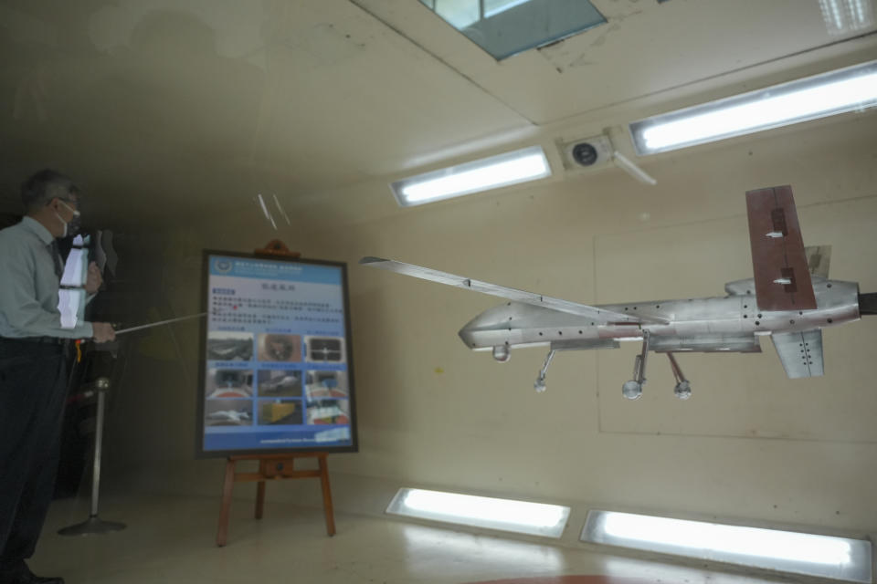 A staffer explains the usage of a scaled UAV model in a wind tunnel for stress testing at the National Chung-Shan Institute of Science and Technology in Taichung in central Taiwan, Tuesday, Nov. 15, 2022. Taiwan displayed its self-developed drone technology Tuesday, amid rising concerns over China's threats to use force to assert its claim to the self-governing island republic. (AP Photo/Walid Berrazeg)