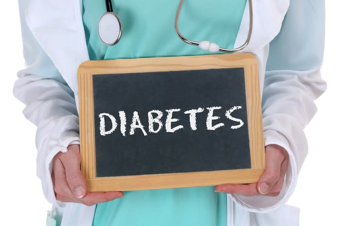 A doctor holding a small chalkboard with word diabetes spelled out in white chalk.