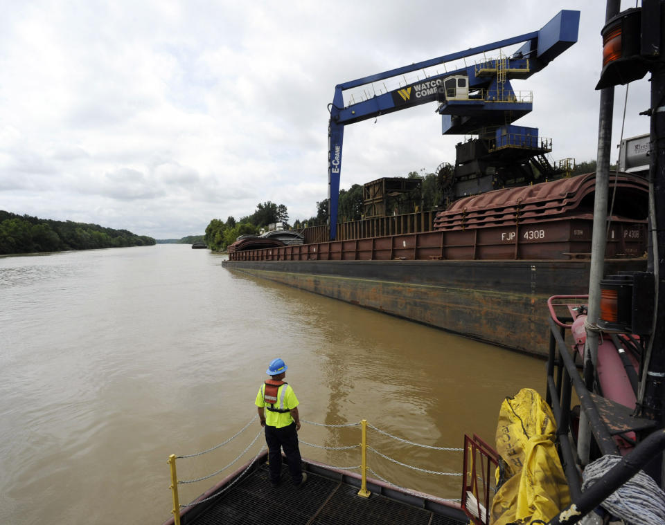 In this Monday, July 22, 2019 photo, a worker watches a crane unload scrap metal along the Tennessee-Tombigbee Waterway in Columbus, Miss. While the waterway hasn't lived up to expectations in terms of traffic or economic development in parts of Alabama and Mississippi, cities including Columbus rely on it for jobs and transportation. (AP Photo/Jay Reeves)