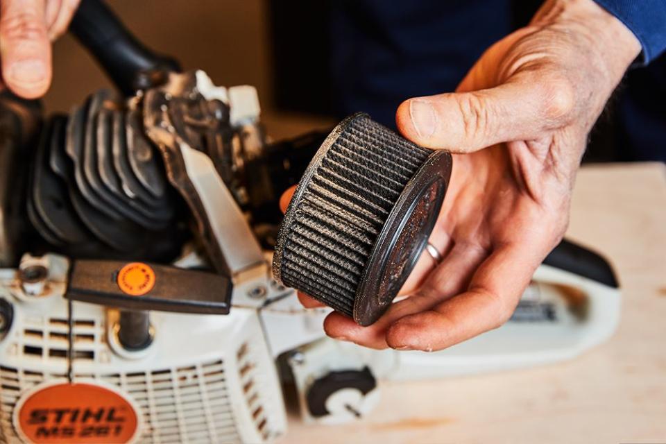 a person holding an air filter from a chainsaw