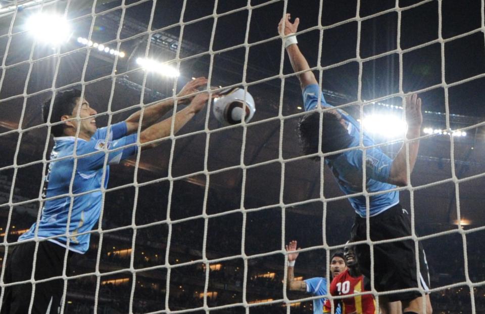 Uruguay's striker Luis Suarez (L) stops the ball with the hand leading to a red card and a penalty for Ghana during the extra-time of 2010 World Cup quarter-final match Uruguay vs. Ghana.