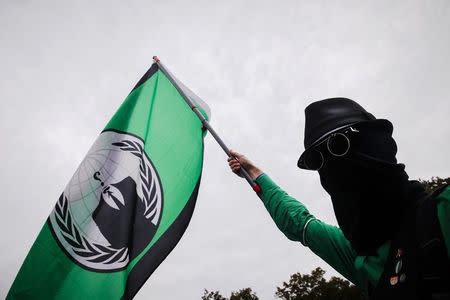 Un hombre sostiene una bandera del grupo hacker Anonymous