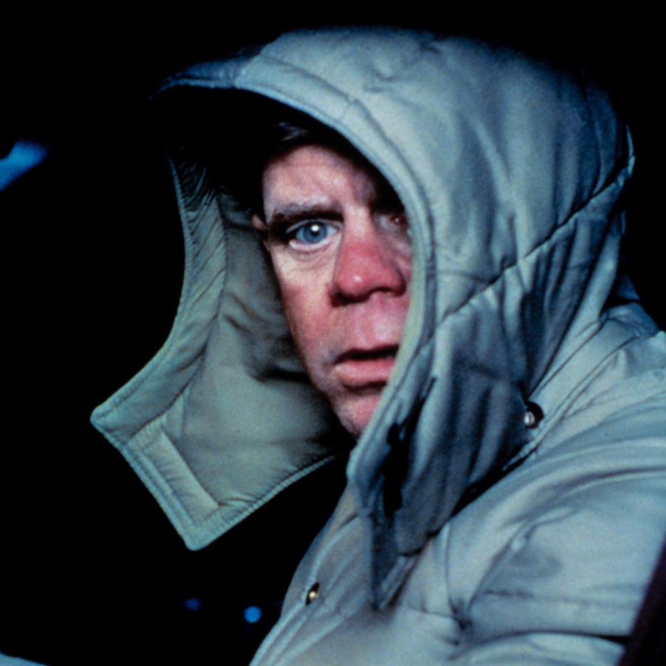 Person in a hooded coat looks concerned while sitting in a vehicle