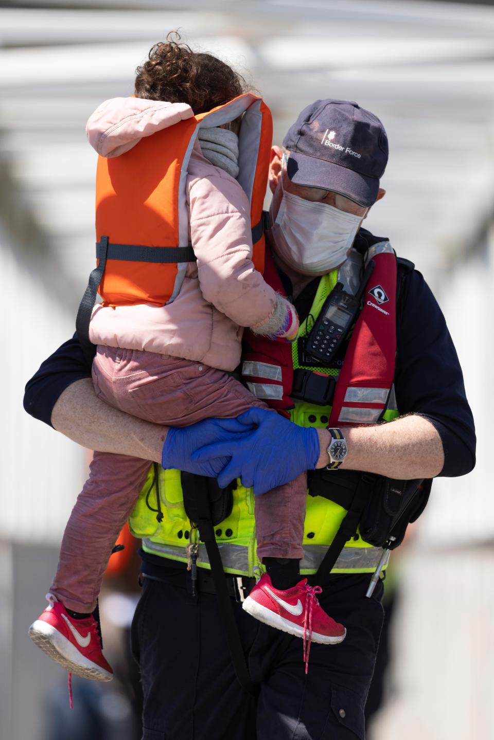 A Border Force official holds a young girl that arrived with other migrants after they were picked up in a dinghy in the English Channel (Getty Images)