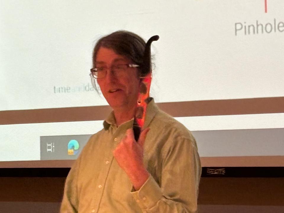 John Martin, an associate professor of astronomy at the University of Illinois Springfield, holds a pair of eclipse glasses while addressing a gathering about the total solar eclipse at Lincoln Library in Springfield on March 21, 2024. The protective eyewear is needed to view the April 8 eclipse anywhere out of the line of totality.