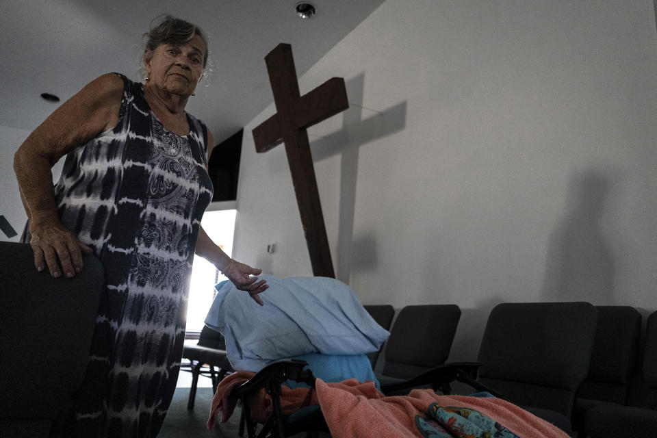 Barbara Wasko stands beside her makeshift bed on the pulpit of the Southwest Baptist Church in Fort Myers, Fla., on Sunday, Oct. 2, 2022. Wasko is living at the church after her home was destroyed by Hurricane Ian. (AP Photo/Robert Bumsted)