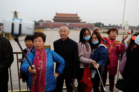 People take pictures of themselves as they attend a flag-raising ceremony at Tiananmen Square a day before the 19th National Congress of the Communist Party of China begins in Beijing, China, October 17, 2017. REUTERS/Damir Sagolj