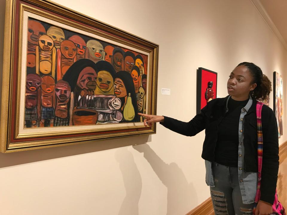 Norfolk State University fine arts senior D'Shea Downey points to her favorite piece of art from the exhibit, "A Taste for the Beautiful: African Impact on American Culture," at Hampton University Museum in Hampton, Virginia, on Friday, Nov. 22, 2019.