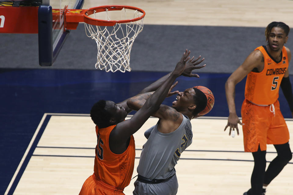 West Virginia forward Gabe Osabuohien (3) shoots while defended by Oklahoma State forward Bernard Kouma (25) during the first half of an NCAA college basketball game Saturday, March 6, 2021, in Morgantown, W.Va. (AP Photo/Kathleen Batten)