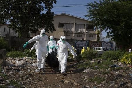 A burial team wearing protective clothing, remove a body of a person suspected of having died of the Ebola virus, in Freetown September 28, 2014. REUTERS/Christopher Black/WHO/Handout via Reuters