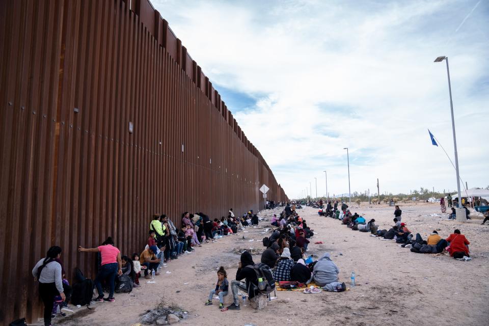 Migrants and asylum seekers wait to be picked up and processed by U.S. Border Patrol agents in Organ Pipe Cactus National Monument along the U.S.-Mexico border about a mile west of Lukeville, Ariz., on Dec. 4, 2023. The Lukeville Port of Entry was closed indefinitely by officials Dec. 4.