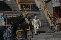 A healthcare worker descends a flight of stairs during a house-to-house campaign to help curb the spread of the new coronavirus in the Mallasa neighborhood of La Paz, Bolivia, Saturday, Aug. 8, 2020. (AP Photo/Juan Karita)