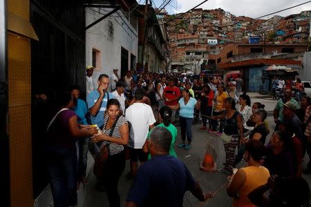 Una mujer recibe dos paquetes de harina de maíz tras hacer fila para comprar comida en un supermercado de Caracas. 17 de marzo de 2017. REUTERS/Carlos Garcia Rawlins