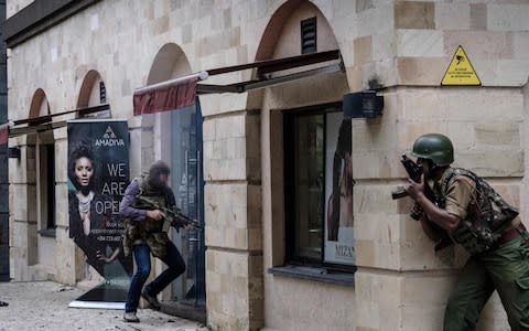 The soldier, carrying his special forces rifle, enters the compound alongside Kenyan security forces - Credit: AFP