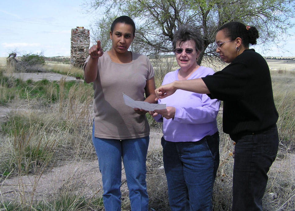 FILE - In this April 26, 2004 file photo Cheryl Robinson, center, and her two daughters, Desiree Marks, left, and Tamara Kamara read a map outlining various landmarks at Wounded Knee, S.D. Ray Robinson, Cheryl's husband and Desiree and Tamara'a father, is believed to have been killed at the site during a 71-standoff between the American Indian Movement and federal agents in 1973. Documents recently released by the FBI to a Buffalo, N.Y., lawyer shed new light on the 40-year-old case of Robinson, an activist and follower of Martin Luther King Jr. The FBI says Robinson was killed during the 1973 occupation of Wounded Knee, and it suspects militant members of the American Indian Movement are responsible. His body was never found. (AP Photo/Carson Walker, File)