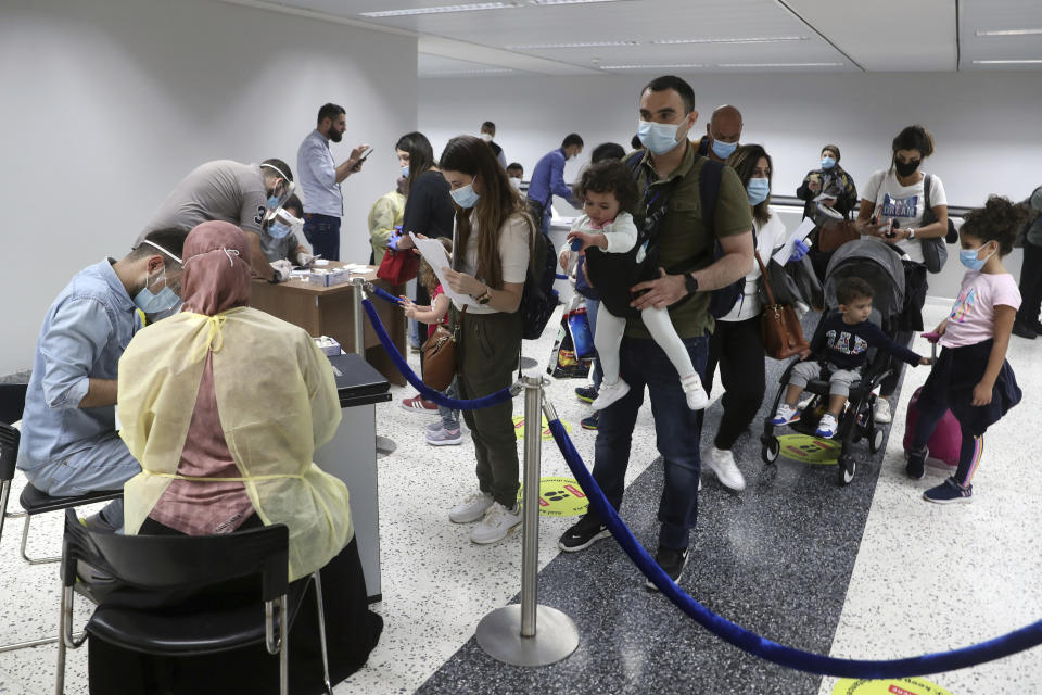 Passengers wait in line to fill a document to undergo a PCR test at the Rafik Hariri International Airport in Beirut, Lebanon, Wednesday, July 1, 2020. Beirut's airport is partially reopening after a three-month shutdown and Lebanon's cash-strapped government is hoping that thousands of Lebanese expatriates will return for the summer, injecting dollars into the country's sinking economy. (AP Photo/Bilal Hussein)Hussein)