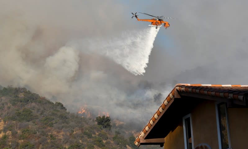 A firefighting helicopter makes a water drop on the Getty Fire as it burns in the hills of West Los Angeles, California