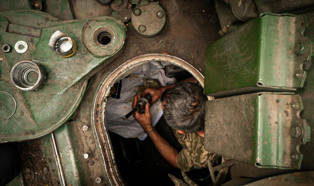 A member of Ukraine's 59th Separate Motorized Infantry Brigade named after Yakiv Handziuk during repair work on a tank near a frontline (EPA)