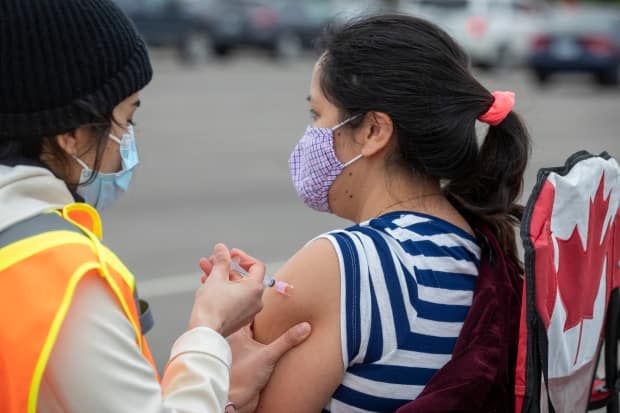 A person receives a COVID-19 vaccine at a drive-thru clinic at Richardson Stadium in Kingston, Ont. (Lars Hagberg/The Canadian Press - image credit)