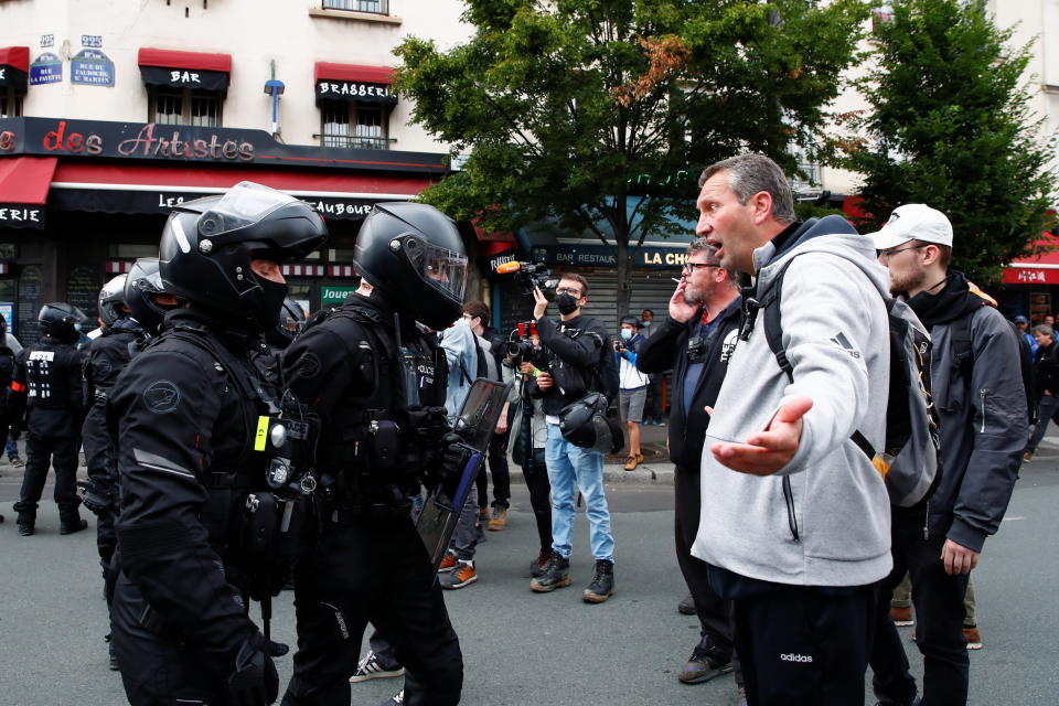 A demonstrator argues with police officers during a protest against the new measures announced by French President Emmanuel Macron to fight the coronavirus disease (COVID-19) outbreak, in Paris, France, July 14, 2021. REUTERS/Gonzalo Fuentes