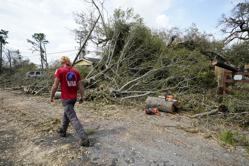 Logan Cunningham, of Canary Tree Service of Jacksonville, Fla., walks past tree debris as he waits for more equipment to arrive, in Lake Charles, La., in the aftermath of Hurricane Laura, Sunday, Aug. 30, 2020. (AP Photo/Gerald Herbert)