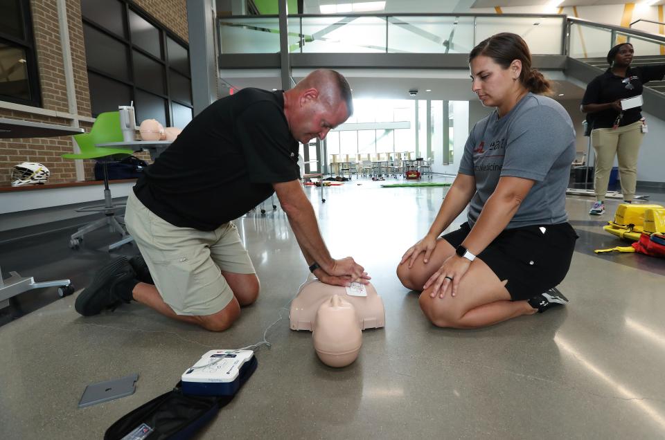 Athletic trainers Willie Henson, left, and Taylor Zuberer use a CPR trainer during an emergency response training session of first responders and athletic trainers at St. Xavier High School in Louisville, Ky. on July 26, 2023.