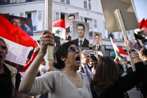 Supporters of the Syrian regime hold portraits of Syrian President Bashar al-Assad as they demonstrate in front of the Syrian cultural center in Paris