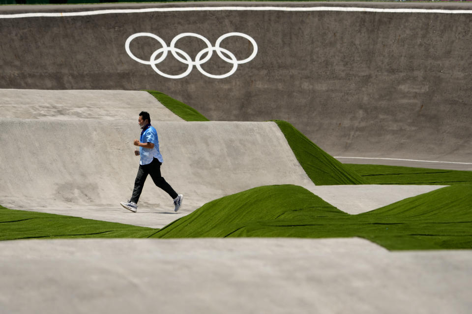 A worker runs across the BMX racing track as preparations continue for the 2020 Summer Olympics, Tuesday, July 20, 2021, at the Ariake Urban Sports Park in Tokyo. (AP Photo/Charlie Riedel)