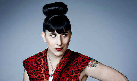 Woman with upper arm tattoo, bright red lipstick, and badass bangs