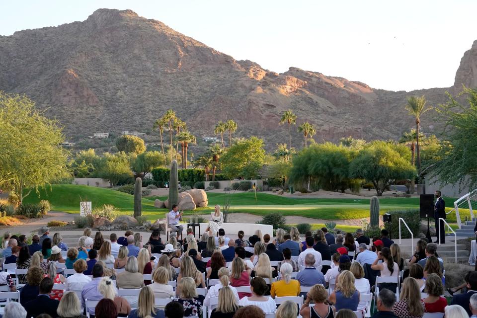 Crowd of people sitting before Ivanka Trump and Hogan Ridley with desert mountains, palm trees, and cactuses in background.