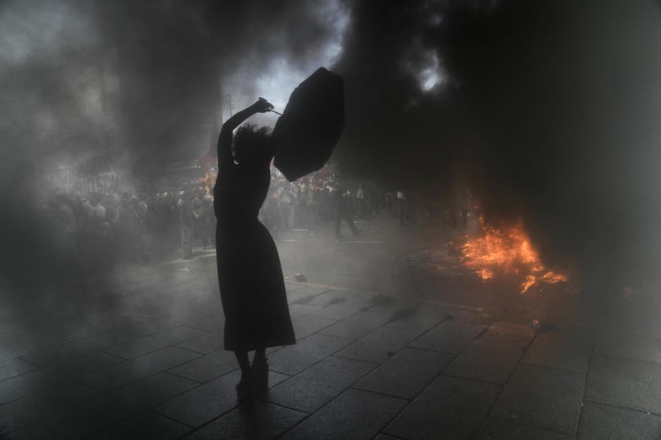 Una mujer que grita consignas contra el gobierno sostiene un paraguas rodeada por nubes de humo durante una manifestación el 10 de marzo de 2022, en Buenos Aires, Argentina, con el fin de protestar por el acuerdo del gobierno con el Fondo Monetario Internacional para refinanciar unos 45.000 millones de dólares de deuda externa. (AP Foto/Rodrigo Abd)