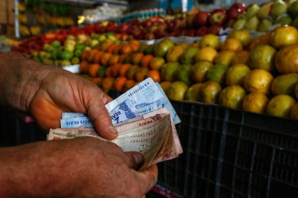 A customer counts money at a fruit and vegetables stall in a market in Salvador, Bahia State, Brazil, on August 26, 2022<span class="copyright">Rafael Martins/AFP —Getty Images</span>