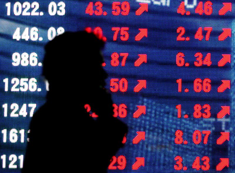 FILE PHOTO: Man is silhouetted against stock quotation board in Tokyo