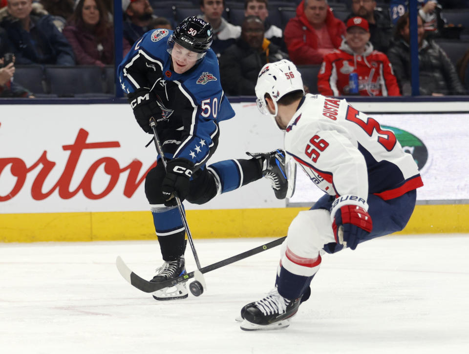 Columbus Blue Jackets forward Eric Robinson, left, shoots the puck in front of Washington Capitals defenseman Erik Gustafsson during the second period of an NHL hockey game in Columbus, Ohio, Tuesday, Jan. 31, 2023. (AP Photo/Paul Vernon)