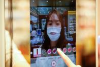 A woman wearing a mask to avoid the spread of the coronavirus disease (COVID-19) shops using AR make up at a cosmetic shop in a department store in Seoul