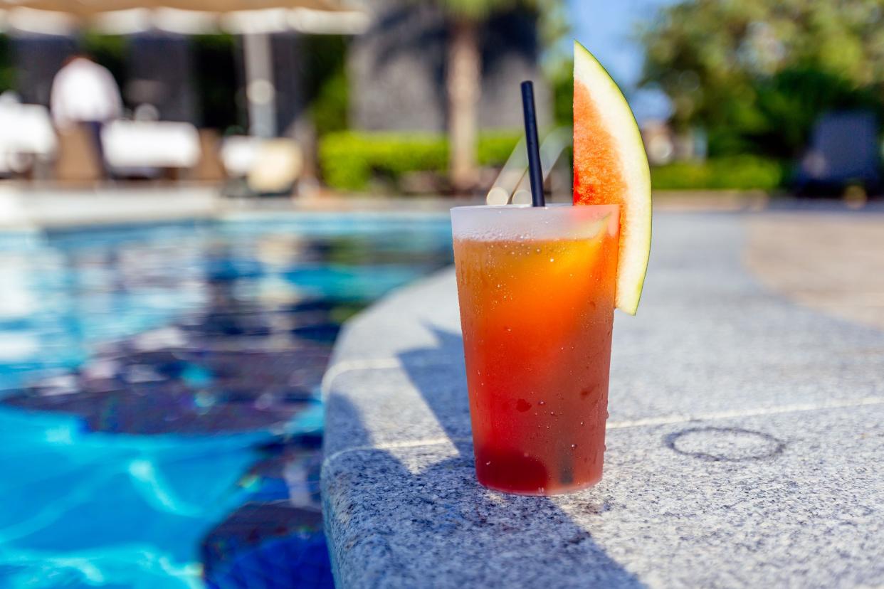 Fresh watermelon cocktail on the ledge of the swimming pool at a resort hotel with a blurred background of the pool and pool area