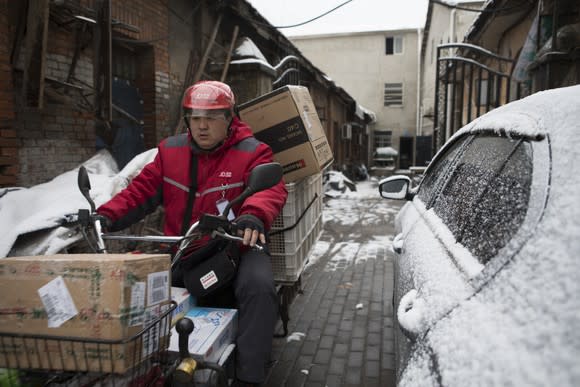 A JD deliveryman non a moped with several boxes.