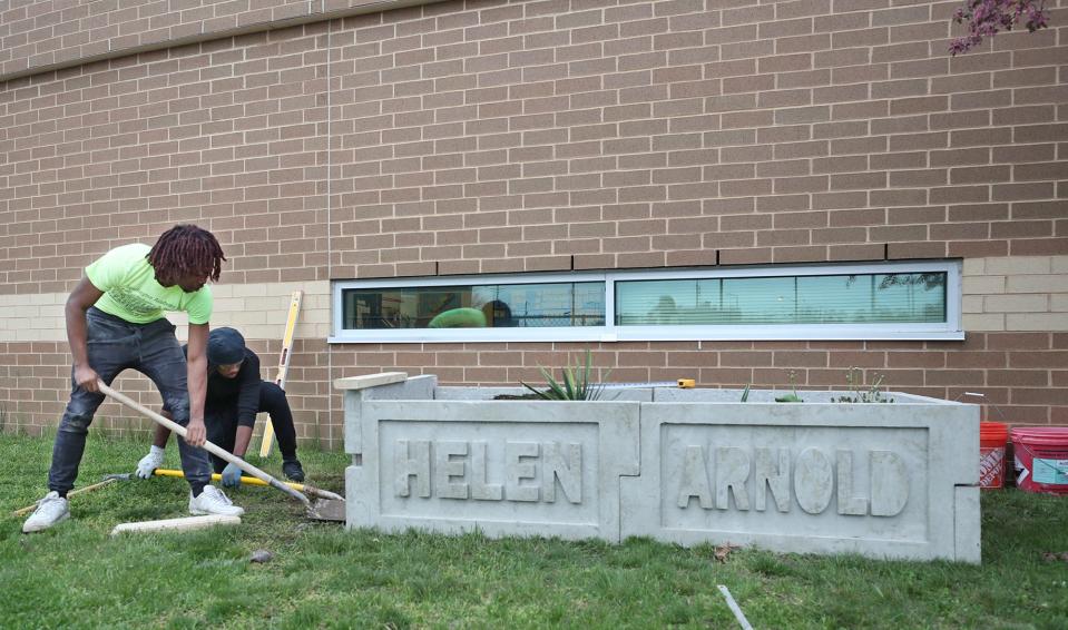 Former Helen Arnold CLC student Mekhi Rice,18, left, works with his Buchtel CLC masonry classmate Justin Clane, 18, as they install the side of a planter at Helen Arnold CLC on Wednesday.