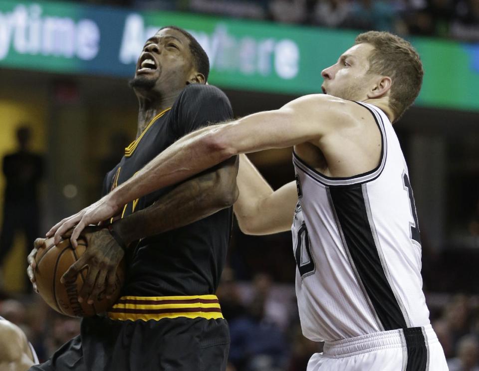 Cleveland Cavaliers' DeAndre Liggins, left, is fouled by San Antonio Spurs' David Lee during the second half of an NBA basketball game, Saturday, Jan. 21, 2017, in Cleveland. The Spurs won 118-115 in overtime. (AP Photo/Tony Dejak)