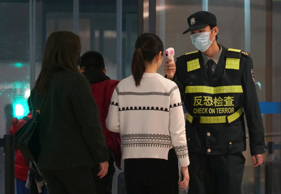 An airport staff member uses a temperature gun to check people leaving Wuhan Tianhe International Airport in Wuhan, China, Tuesday, Jan. 21, 2020. Heightened precautions were being taken in China and elsewhere Tuesday as governments strove to control the outbreak of a novel coronavirus that threatens to grow during the Lunar New Year travel rush. (AP Photo/Dake Kang)