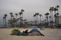 A homeless man goes through his belongings outside his tent pitched on the beach in the Venice neighborhood of Los Angeles, Tuesday, June 29, 2021. The proliferation of homeless encampments on Venice Beach has sparked an outcry from residents and created a political spat among Los Angeles leaders. (AP Photo/Jae C. Hong)