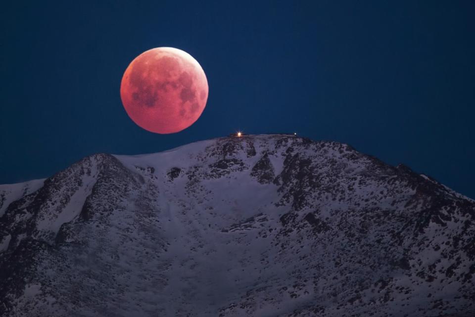 Scenic view of snowcapped mountain against sky at night with large full moon