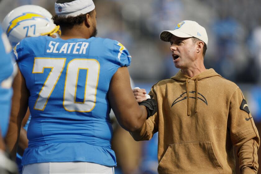 Chargers coach Brandon Staley greets offensive lineman Rashawn Slater.