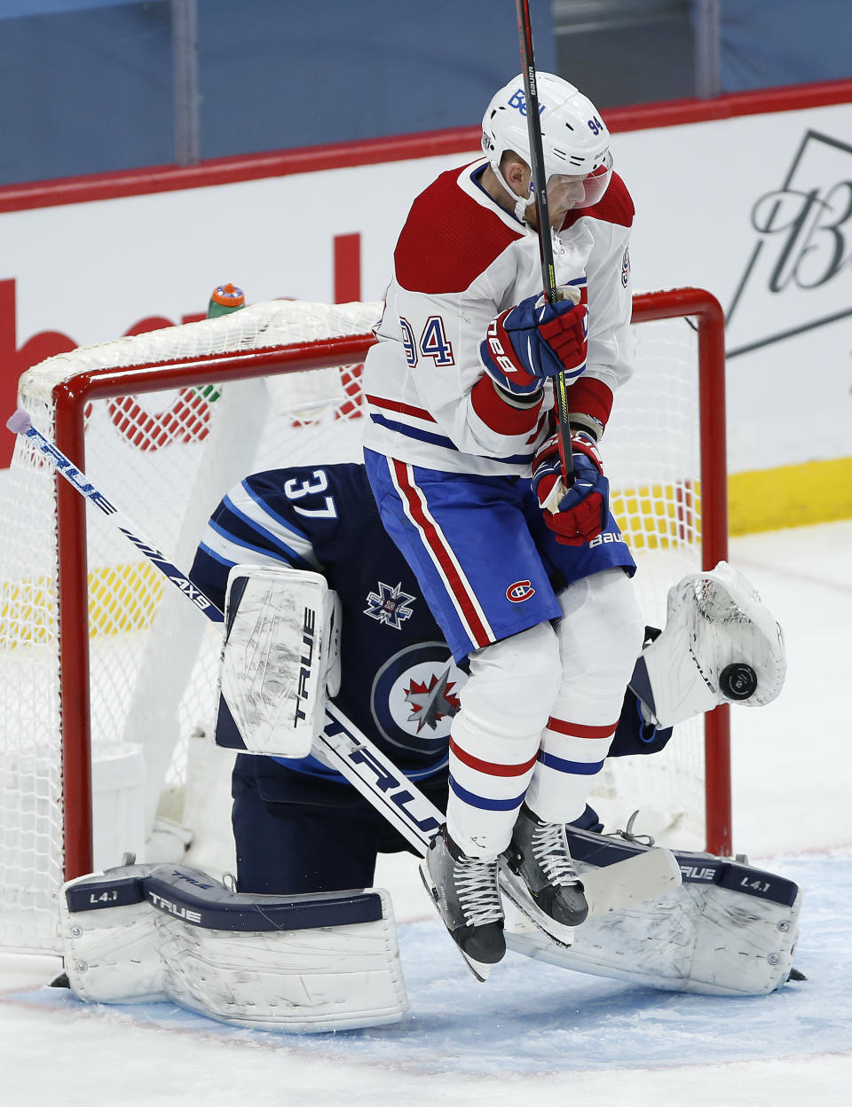 Winnipeg Jets goaltender Connor Hellebuyck (37) makes a save as Montreal Canadiens' Corey Perry (94) screens him during the second period of an NHL hockey game Saturday, Feb. 27, 2021, in Winnipeg, Manitoba. (John Woods/The Canadian Press via AP)